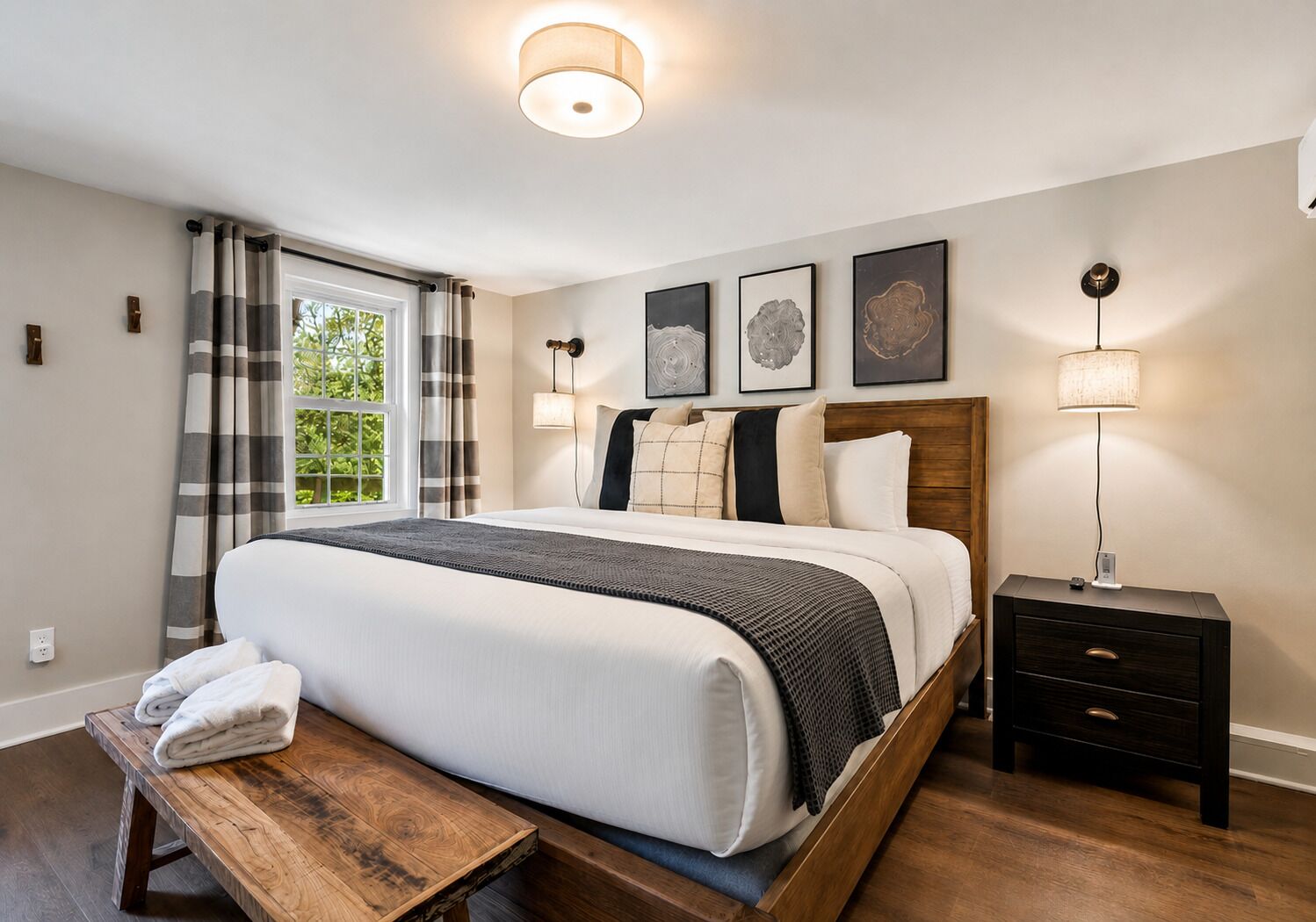 Een slaapkamer met een bed, nachtkastjes, een bankje en kunst aan de muur.