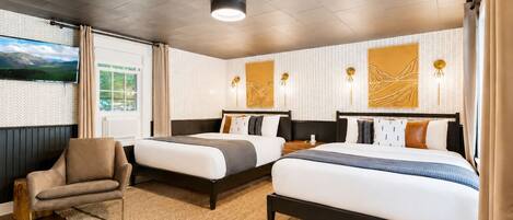 A hotel room with two beds, a sofa, a TV, and artwork on the walls.