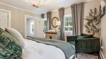 Un dormitorio con una cama grande, un aparador, una silla y una ventana con cortinas.