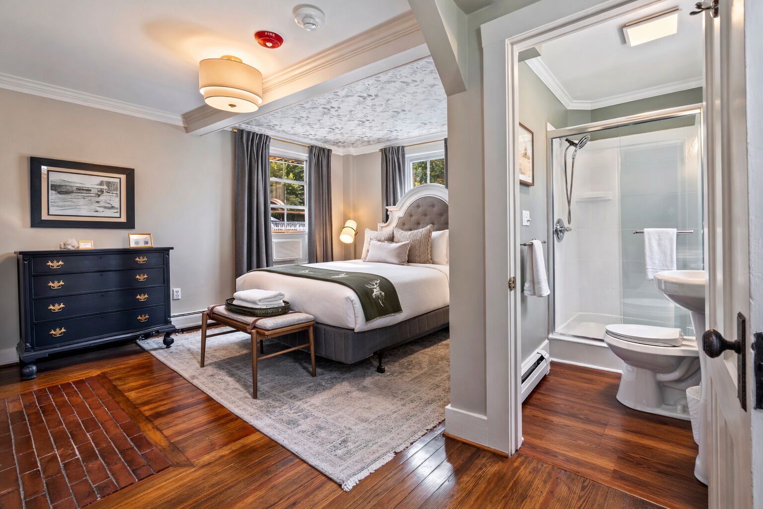 Ein Schlafzimmer mit Bett, Kommode und Blick ins Badezimmer.