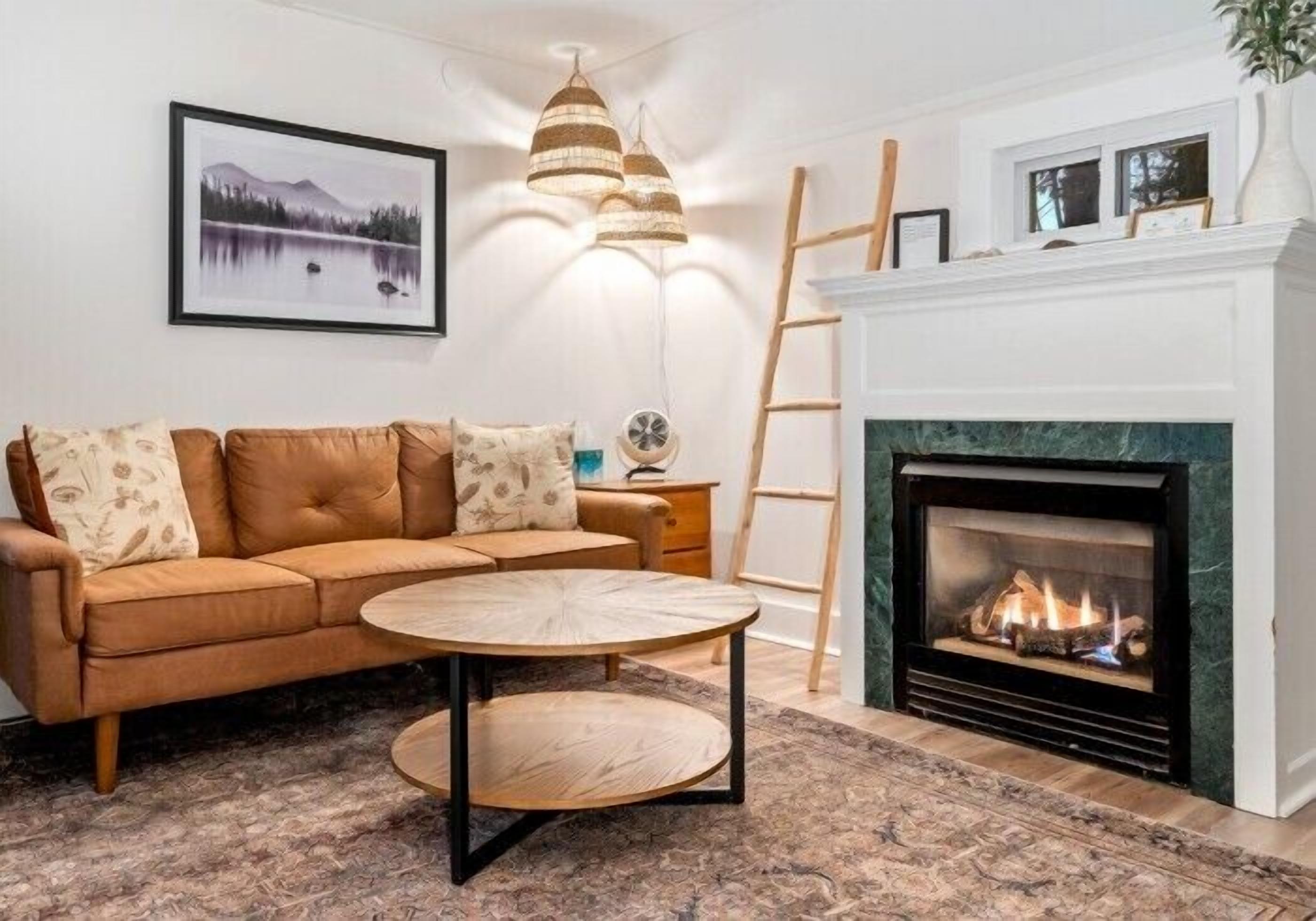 A living room with a sofa, a round coffee table, a fireplace, and a framed picture on the wall.