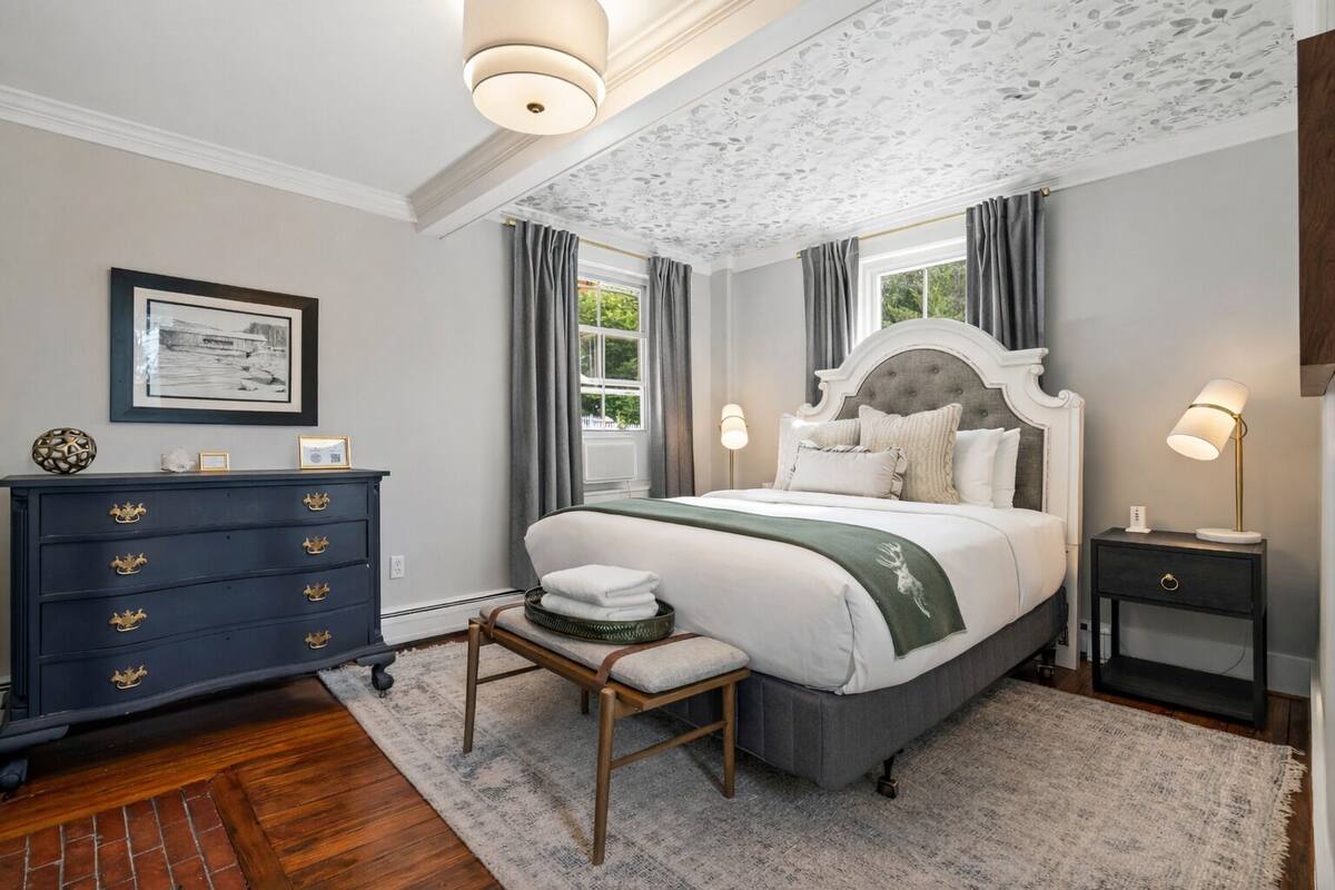 A bedroom with a bed, dresser, nightstand, and a small table with a chair.