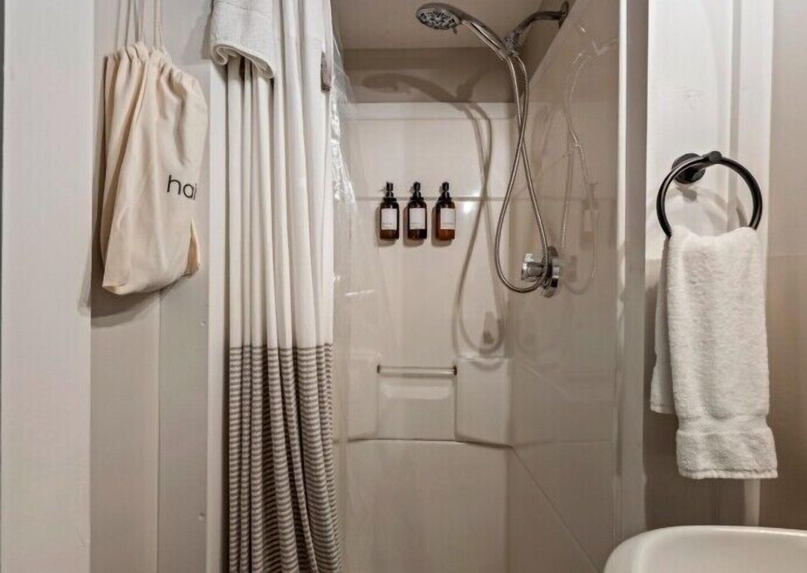 A bathroom with a shower, a towel rack, and a hanging towel.