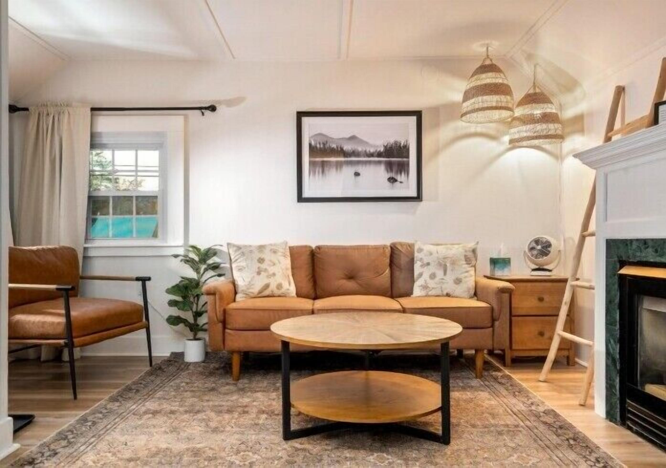 Una sala de estar con un sofá, una mesa de centro, una chimenea y un cuadro en la pared.