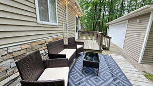 Eine überdachte Terrasse mit Korbmöbeln und einem gemusterten Teppich.