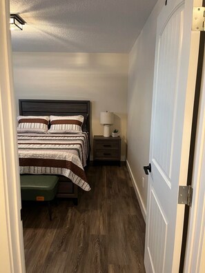 A bedroom with a bed, bedside table, lamp, and a green bench. - 2 bedroom upper level of home in Grande Prairie  (Grande Prairie)