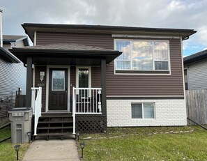 A two-story house with a front porch, a mailbox, and a number sign. - 2 bedroom upper level of home in Grande Prairie  (Grande Prairie)