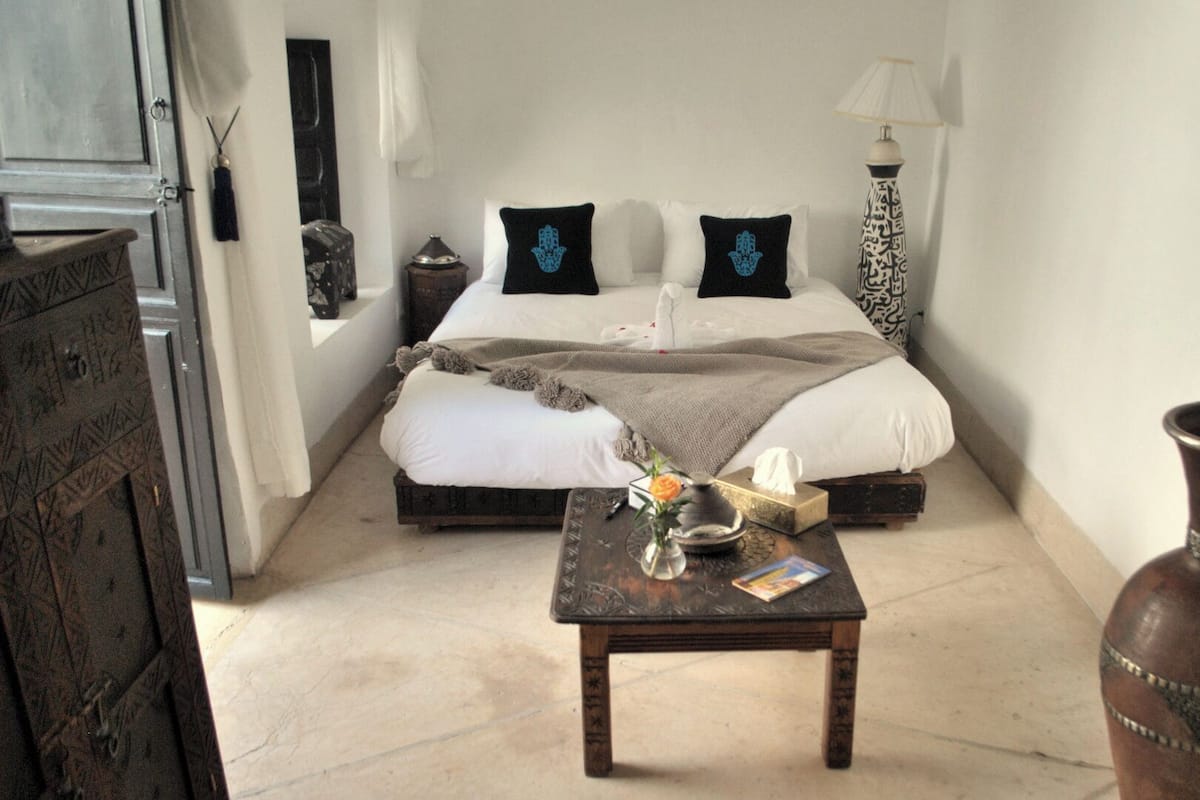 A bedroom with a bed, bedside table, lamp, and a vase.