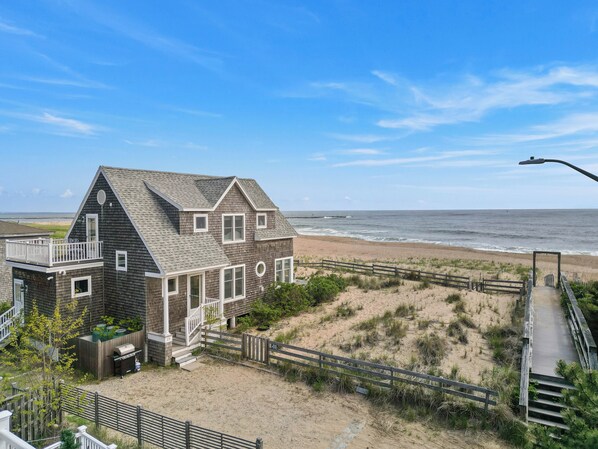 A two-story house with a balcony overlooking a beach.