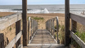 A wooden boardwalk leading to the beach with a clear view of the ocean.