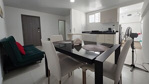 A modern living room with a dining table, a sofa, and a kitchenette. - Apartaestudios San Fernando (Cali)