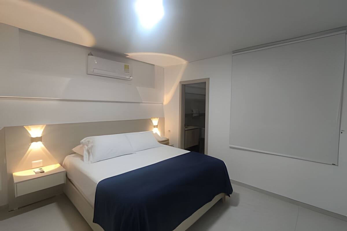 A bedroom with a bed, bedside lamps, a wardrobe, and a ceiling light.