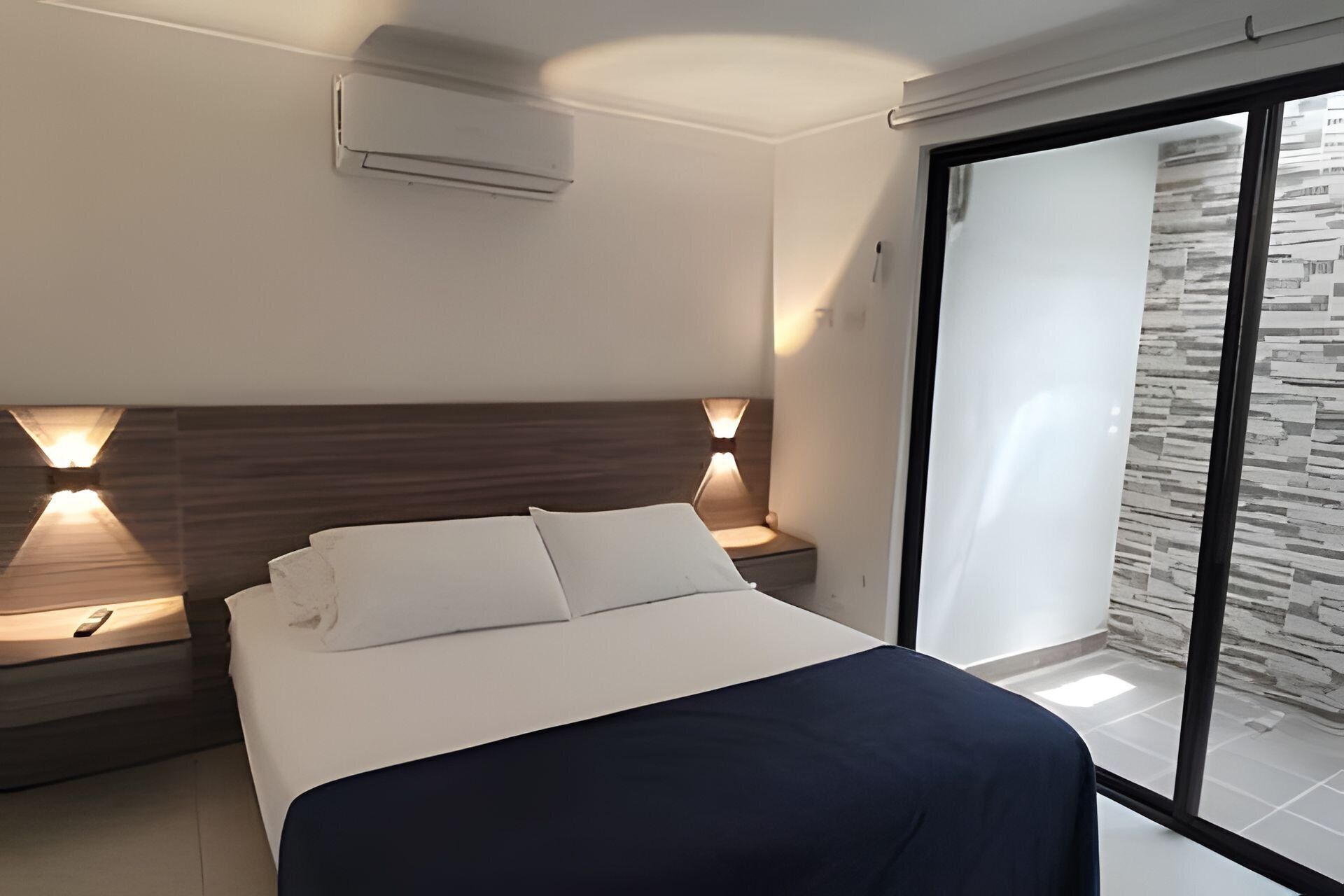 Ein modernes Schlafzimmer mit einem Bett, Nachttischlampen und einer Klimaanlage.