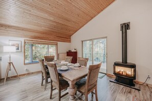 Enjoy meals in this dining area with a table for four, a wood-burning stove, and a high ceiling.