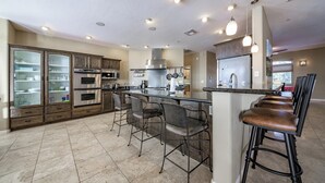 Una cocina moderna con una isla central, taburetes de bar y electrodomésticos integrados.