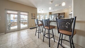 Cocina con barra, que incluye dos taburetes con motivos de animales, un refrigerador y un microondas.