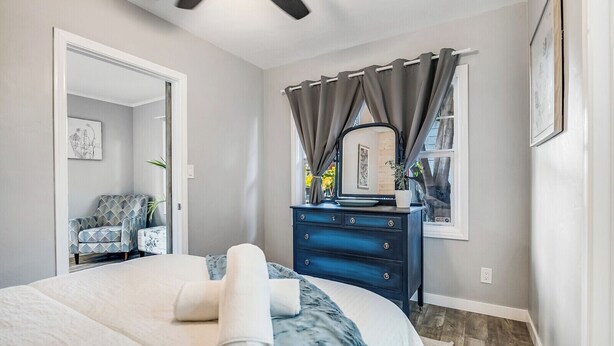 A bedroom with a bed, a dresser, a chair, and a window with curtains.