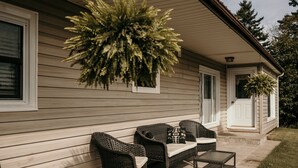 A patio with wicker furniture and a hanging plant. - The Urban Oasis (Tignish)
