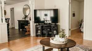 A living room with a TV, entertainment center, and a round coffee table with a decorative tray. - The Urban Oasis (Tignish)