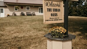 A welcome sign for The Urban Oasis with a flower arrangement. - The Urban Oasis (Tignish)