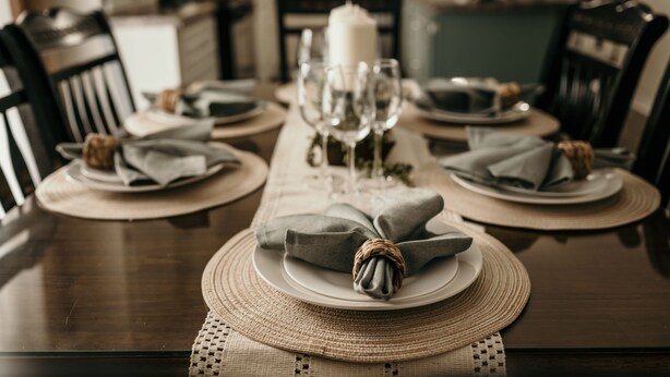 A dining table set with plates, glasses, and napkins. - The Urban Oasis (Tignish)