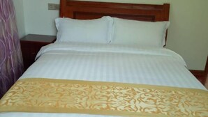 Una cama bien tendida con un cabecero de madera, una mesita de noche y una manta decorativa.