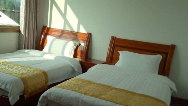 Dos camas individuales con cabeceros de madera, ropa de cama blanca y un detalle decorativo amarillo.