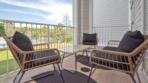 A balcony with wicker furniture and a glass table, overlooking a pool and greenery. - Disney Fab4, Stitch, Lady!Come enjoy a Magical vacation so close to WDW and more (Kissimmee)