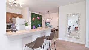 A modern kitchen with a bar area, two bar stools, a decorative mirror, and a green wall with neon signs. - Disney Fab4, Stitch, Lady!Come enjoy a Magical vacation so close to WDW and more (Kissimmee)