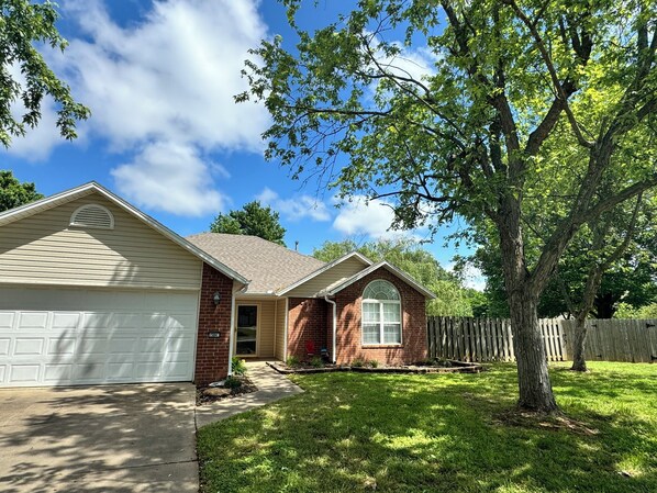 A two-story house with a garage, a front yard, and a wooden fence.