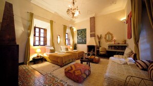 A traditional room with two beds, a chandelier, a fireplace, and a mirror. - Riad Chambres d'Amis (Marrakech)