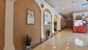 A hallway with a polished floor, white columns, and framed informational signs on the walls.