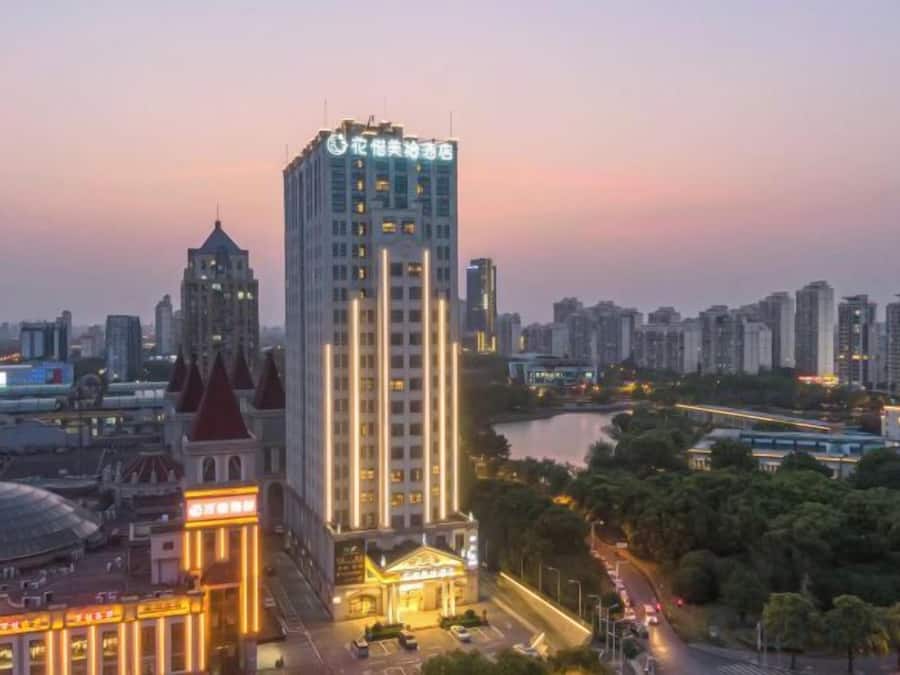Un hotel de gran altura con una torre destacada, rodeado por un paisaje urbano y un río.