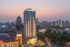 A high-rise hotel with a prominent tower, surrounded by a cityscape and a river.
