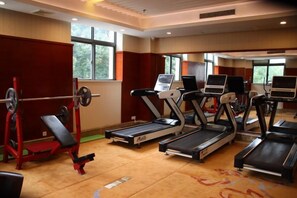 Une salle de sport équipée de tapis de course, d’un banc de musculation et d’un appareil d’aviron.
