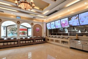 A buffet area with multiple food display cases and a digital menu board.
