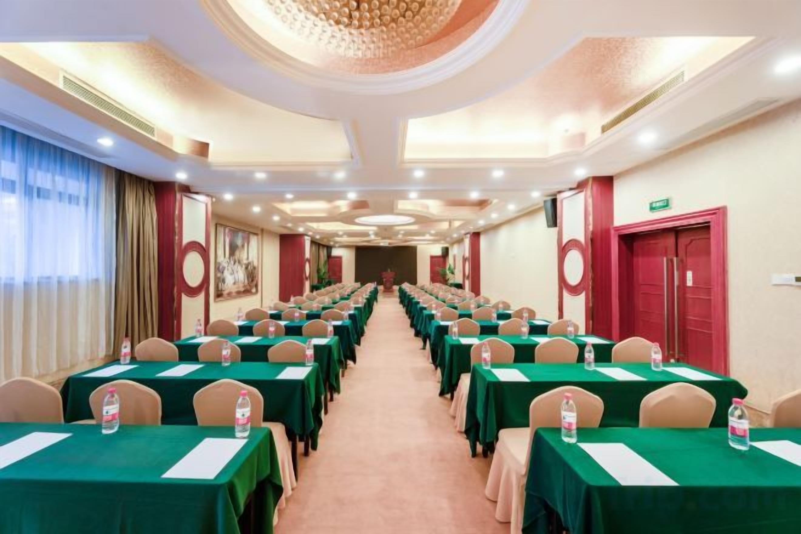 Un salón de conferencias con filas de mesas, sillas y una mesa grande en el centro.