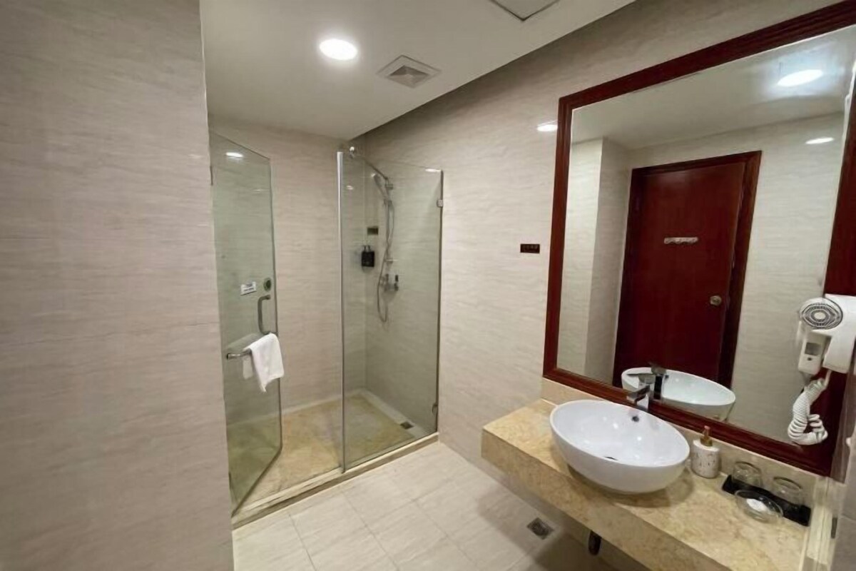A modern bathroom with a glass-enclosed shower, a large mirror, and a sink with a vanity.