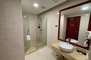 Un baño moderno con ducha de vidrio, un espejo grande y un lavabo con tocador.