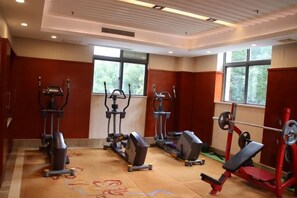 Academia com máquinas de cardio, equipamentos de musculação e amplas janelas.