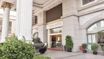 A Vienna Hotel entrance with a grand facade, columns, and potted plants.