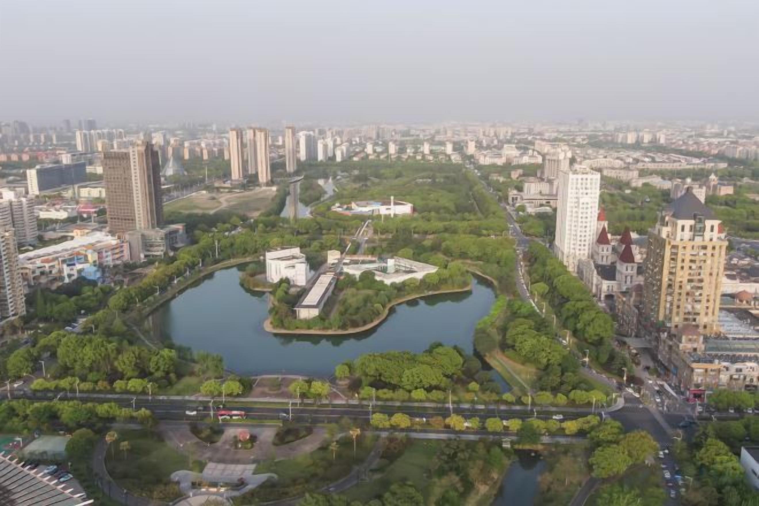 Paisatge urbà amb un parc central, un riu i alts edificis al voltant.