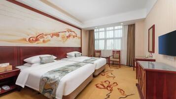 A hotel room with a large bed, a desk, a TV, and a painting on the wall.
