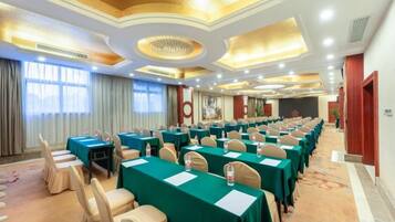 A conference room with rows of tables and chairs, a carpeted floor, and a decorative ceiling.