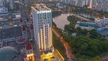 Un hotel moderno de gran altura con un letrero llamativo, rodeado por un río y el paisaje urbano.