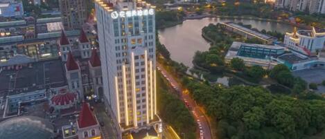 A high-rise hotel with a prominent sign, surrounded by a river and urban landscape.