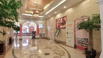 A hotel lobby with a polished floor, a chandelier, and a large potted plant.