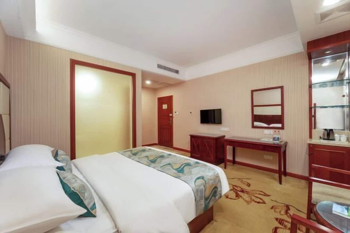 A hotel room with a bed, a desk, a television, and a wardrobe.