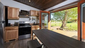 A modern kitchen with wooden cabinets, stainless steel appliances, and a large dining table. - Oakley`s Oasis - Honeymoon Suite (Paonia)