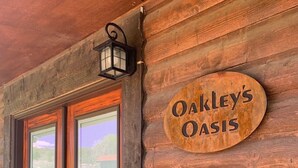 A wooden log cabin entrance with a glass door and a sign that reads "Oakley's Oasis". - Oakley`s Oasis - Honeymoon Suite (Paonia)
